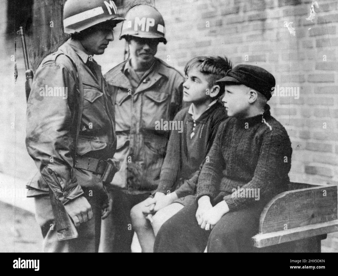 La question du député de Yank Aachen les tireurs d'élite d'enfants : Willy Etschenberg, 14 ans, et Hubert Heinrichs, 10 ans, (à droite) sont interrogés par la police militaire américaine après avoir été pris en train de s'empader des troupes américaines entrant à Aix-la-Chapelle, en Allemagne. Ils ont dit qu'on leur avait appris à faire demi-bévue par le mouvement des jeunes d'Hitler, dont ils sont membres. 3 novembre 1944. (Photo par photo de presse associée). Banque D'Images