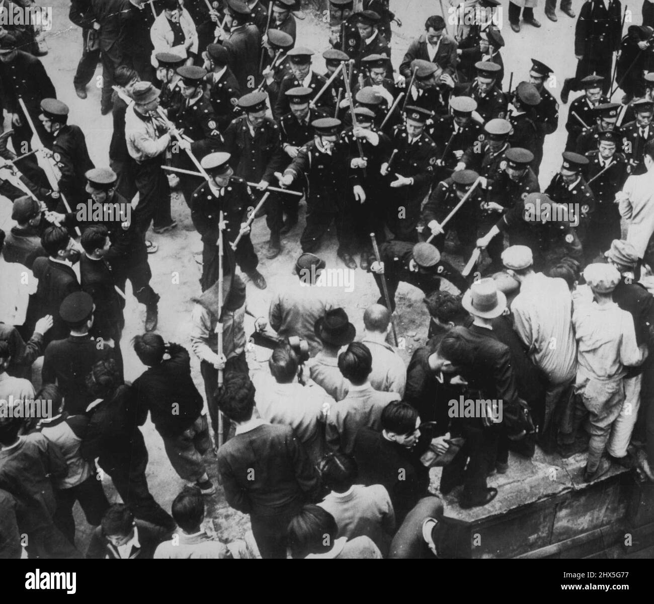 La police de Tokyo s'emmêle avec les rouges - plusieurs communistes se tiennent sur place alors que la police de Tokyo intervient pour briser une réunion le 31 mai. Les Reds sont restés trop longtemps à l'heure de leur réunion. Plusieurs Reds et la police ont été renversés dans des éraflures. Un policier est renversé (jambes en haut à gauche) tandis que d'autres policiers portant des bâtons de quatre pieds bloquent d'autres manifestants. Plusieurs policiers se concentrent sur un manifestant tombé (à droite) qui est caché par la foule. 02 juin 1949. (Photo par AP Wirephoto). Banque D'Images