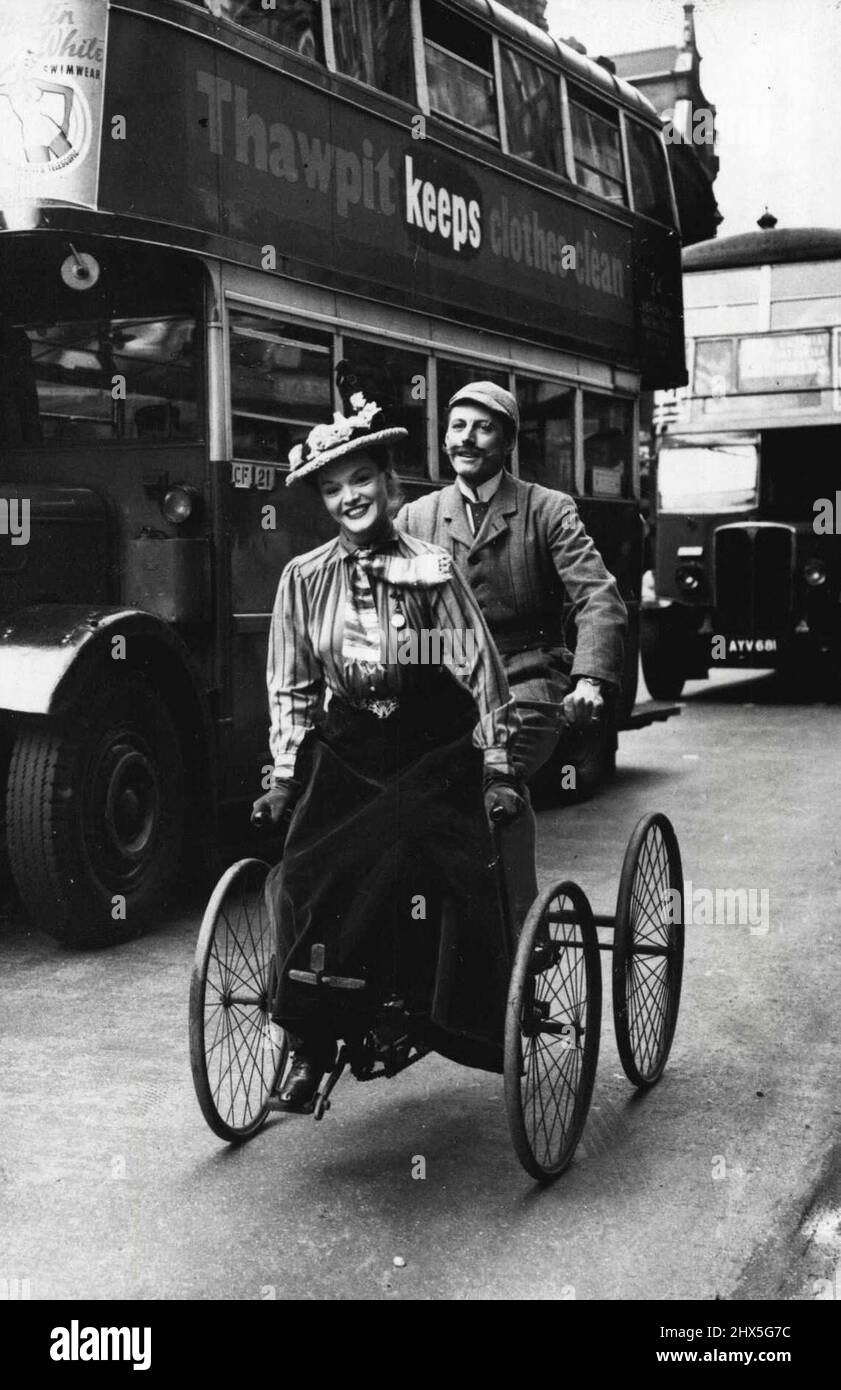 Défilé de « 100 ans de mode » à Londres -- Roberta Huby, la jeune star de la comédie musicale, avec M. Geoffrey Steele, arrivant sur un ancien vélo à quatre roues, portant des costumes édouardiens, pour la parade. Plusieurs et variés ont été les costumes anciens vus dans le cadre de l'échange de '100 ans de la mode' présenté par la Chambre de commerce de Drapers au théâtre Wyndhams, Londres, commémorant le 50th anniversaire de la fondation de la Chambre. 17 mai 1949. (Photo de Sport & General Press Agency, Limited). Banque D'Images