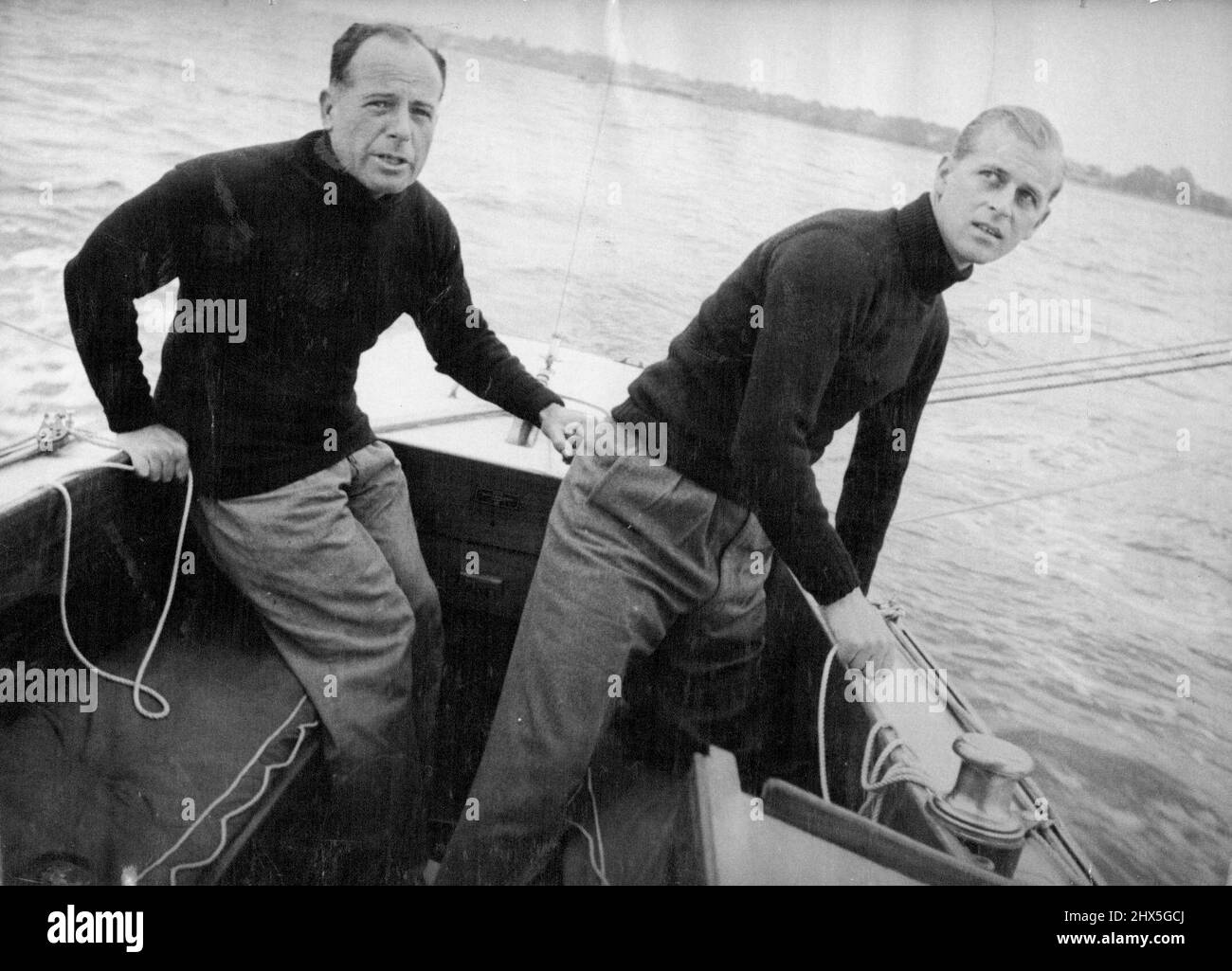 Le duc d'Édimbourg à bord de la « Bluebottle » -- tailler le spinnaker en courant avant le vent le duc d'Édimbourg avec le lieutenant-commandant Michael Crochton, le timonier du yacht. Le "Bluebottle", un yacht du verre Dragon (app. l8ft. Long) a été présenté à leurs Altesses Royales la princesse Elizabeth et le duc d'Édimbourg par le Island Sailing Club. Le duc a contesté sa première course sur le yacht lorsqu'il est entré dans le « Bluebottle » lors d'un récent événement de yachting à Cowes. Dans l'équipage de trois bateaux, le duc a agi comme troisième main. Le premier jour, 'Bluebottle' est venu en troisième mais disqual Banque D'Images