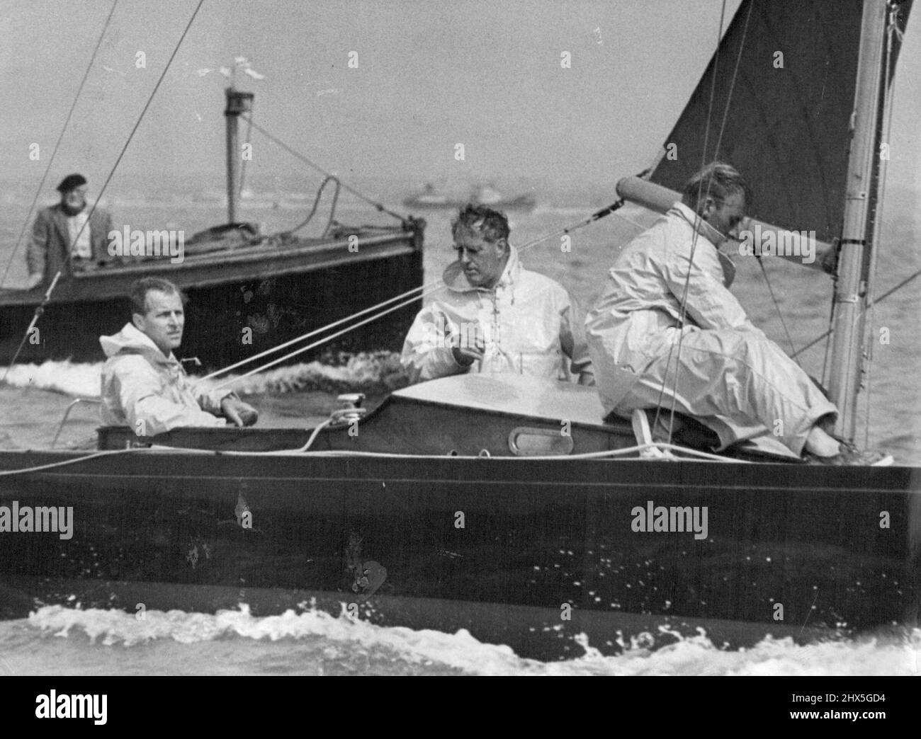 Sportif polyvalent le duc d'Édimbourg à la barre du yacht Bluebottle, en compétition à Cowes Regatta. Le Duke est un bon joueur de cricket et de polo. Lors d'une course sous le vent à une régate de Cowes, le duc d'Édimbourg dirige un Bluebottle de classe Dragon qui a de bonnes chances de gagner le droit de représenter aux Jeux Olympiques de Melbourne. UFFA Fox est le compagnon burly debout dans le cockpit. 25 août 1953. Banque D'Images