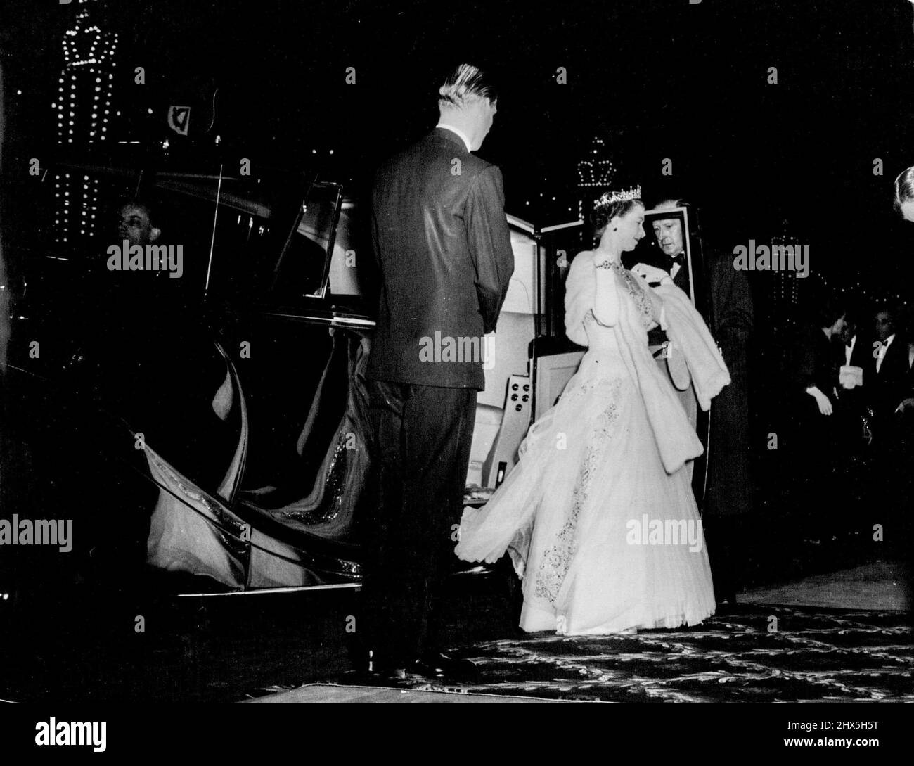 La Reine au milieu des lumières de Blackpool. Sur fond de couronnes formées par les célèbres illuminations de Blackpool, la reine, resplendissant dans une robe en filet blanche brodée d'argent et un circlet étincelant (tiara en bijoux), arrive à l'Opéra de Blackpool pour la Royal Variety Performance de la nuit dernière. Il s'agissait du premier spectacle Variety Command à avoir lieu à l'extérieur de Londres et a été organisé dans le cadre de la visite royale actuelle du Lancashire. 14 avril 1955. (Photo de Reuterphoto). Banque D'Images