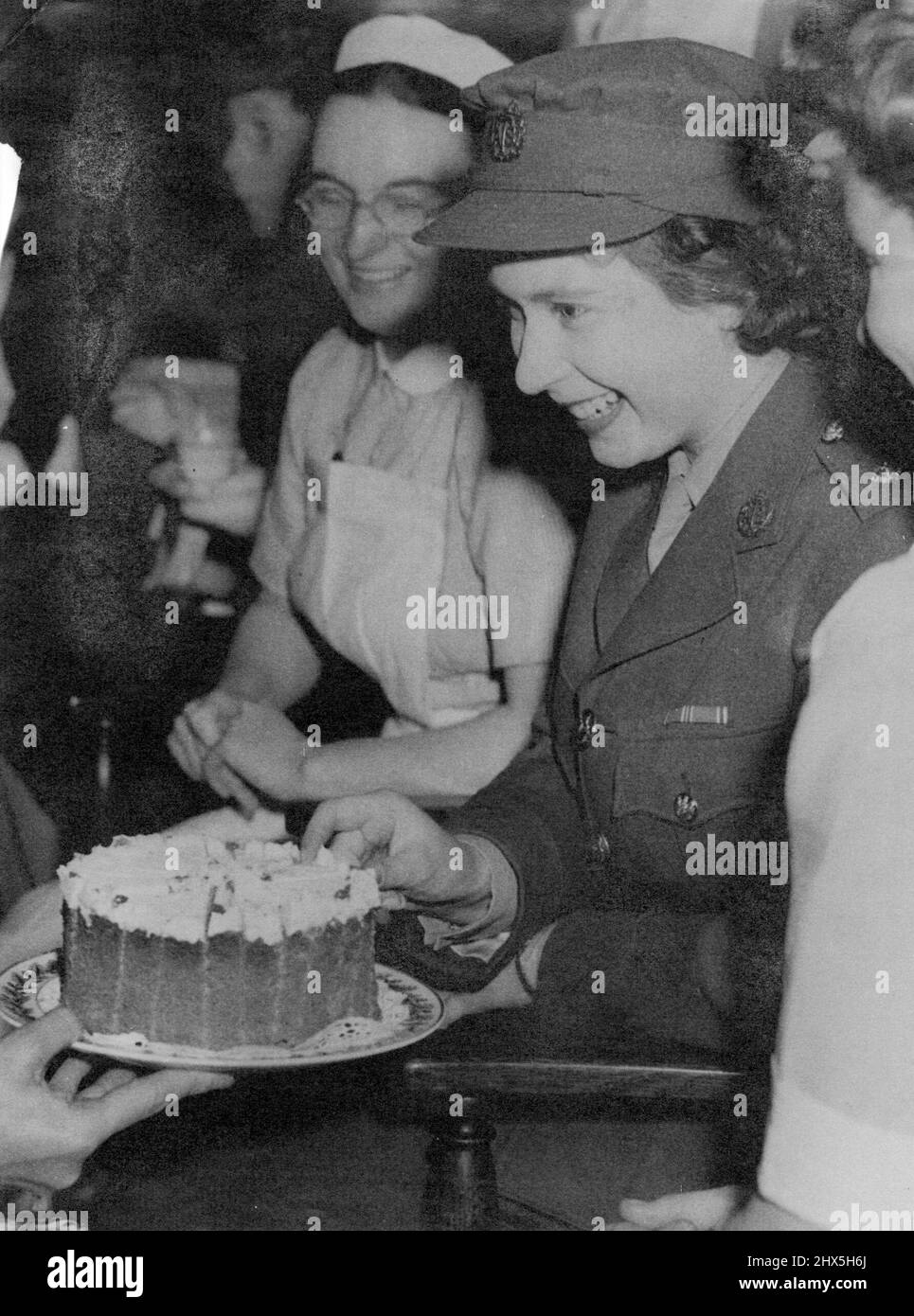 La princesse Elizabeth visite le Royal College of Nursing. La princesse, avec les membres de l'Association des infirmières étudiantes, prend un morceau de gâteau au thé qui a suivi son adresse à l'Association. La princesse Elizabeth, qui préside pour la première fois à une réunion de l'Association des infirmières étudiantes, au Royal College of Nursing, à Londres, a reçu un chèque de £2,500 pour la Royal Navy par des unités de l'Association. Après avoir pris la parole, lorsqu'on lui a présenté un pont argenté de S.N.A., la princesse Elizabeth a pris le thé avec les membres. 5 juillet 1945. (Photo par Banque D'Images