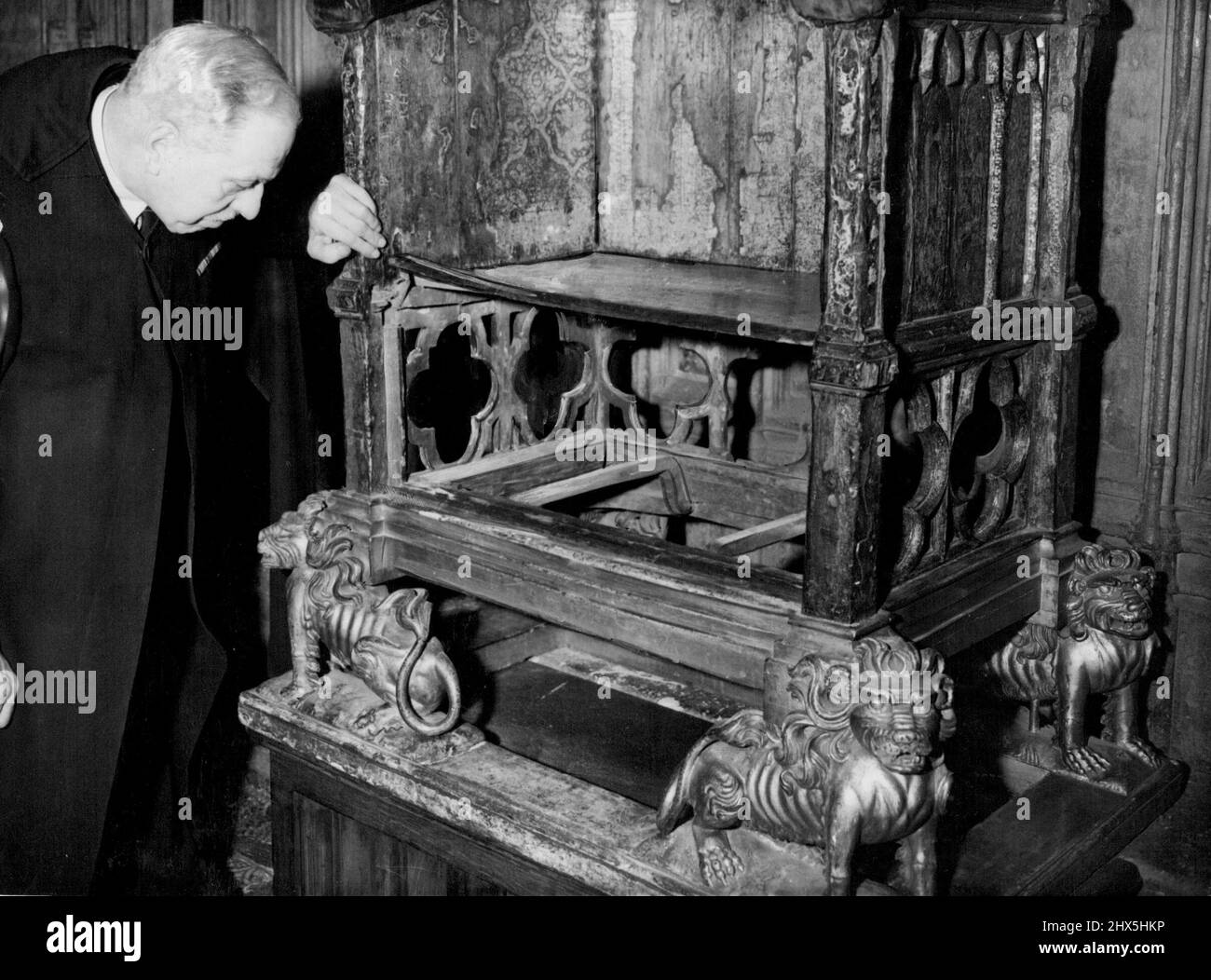 The Coronation Stone Stolen -- un fonctionnaire de l'abbaye de Westminster est vu inspecter la chaise de Coronation dans l'abbaye, ce matin, le 27 décembre. La pierre utilisée pour reposer sous le siège. Notez le bord gauche du siège. Ce dommage a été causé lorsque la pierre a été tirée depuis le dessous du siège. Juste au-dessus de la queue du lion doré (à gauche) ont été rayés les initiales 'J.D.s'. La pierre de Coronation a été volée tôt sur chaise à l'abbaye de Westminster, où elle s'était reposée pendant 650 ans. La pierre, de grès jaune et pesant plus de quatre cents poids, a été apportée en Angleterre par le roi Edward I, Banque D'Images