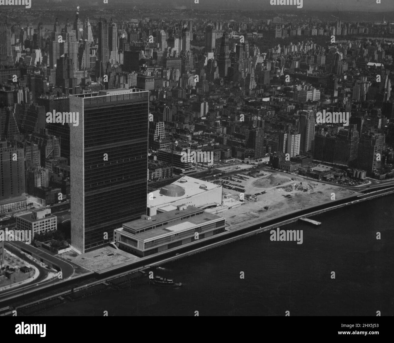 Siège des Nations Unies à New York -- vue aérienne du centre-ville de Manhattan, New York. Le nouveau Siège permanent de l'Organisation des Nations Unies est au premier plan, dans la zone dégagée le long de la rive est de la rivière. Les quatre bâtiments de l'ONU vus sur cette photo sont: Le bâtiment réservé à la zone de conférence et qui est situé au premier plan, le long de la rive de la rivière est; le bâtiment du Secrétariat, qui est de 550ft. De hauteur et qui est au centre, au premier plan, derrière la zone de conférence; Le bâtiment réservé à l'usage de l'Assemblée générale, vu à gauche, à l'arrière du Secrétariat Banque D'Images