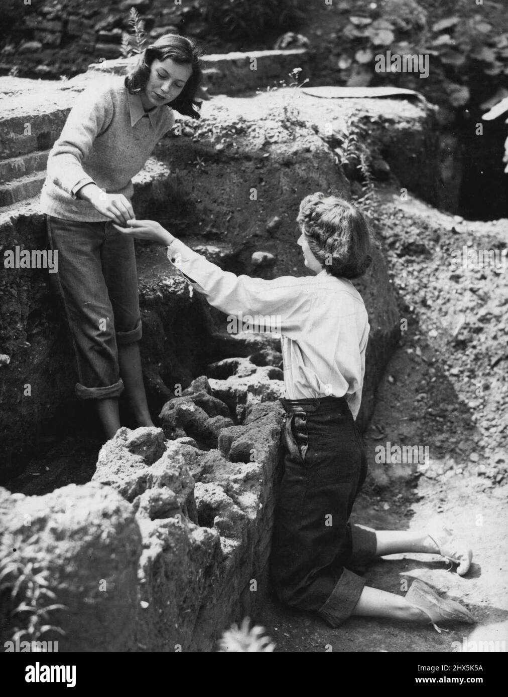 Les étudiants américains à la recherche de Roman London -- l'examen d'une recherche sur le site bombardé à ce jour sont, à gauche, Mlle. Marianne Moore, de Washington, et Mlle. Charlotte Fitzpatrick, de St. Paul. Des étudiants américains en archéologie, ici à la recherche de vestiges romains à Londres et dans d'autres villes romaines, ont commencé à travailler ce matin (mardi) sur un site bombardé à King's Head Yard, Borough High Street, Southwark, Londres. 30 juillet 1946. (Photo de Reuterphotos). Banque D'Images