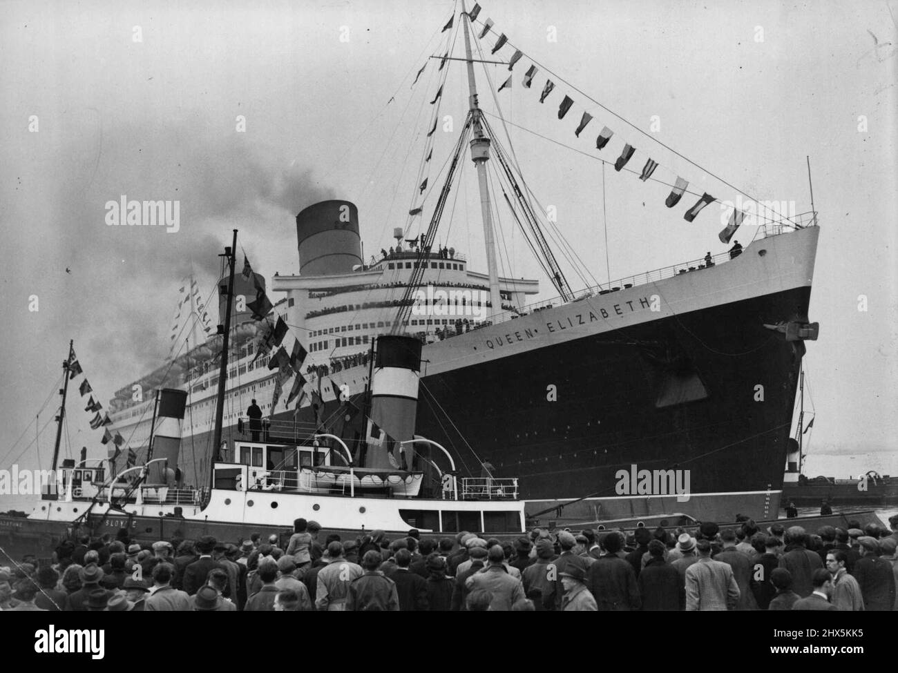 « La reine Elizabeth » va en mer -- les foules du côté du quai donnent un chaleureux envoi de la « reine Elizabeth » car, déchorée de bunkers, elle quitte son poste d'amarrage à Southampton aujourd'hui (mercredi). À seulement deux heures cet après-midi (mercredi), le paquebot de 83 000 tonnes Cunard-White Star, la reine Elizabeth, a défait ses amarrages à Southampton et s'est lentement glissé de son berth pour devenir son premier voyage passager à New York. Une grande foule se rassemblait du côté du quai a donné au navire un départ en route, d'autres navires dans l'eau de Southampton ont sonné leurs sirènes au revoir alors qu'elle s'était rassemblée. 16 octobre 1946. Banque D'Images