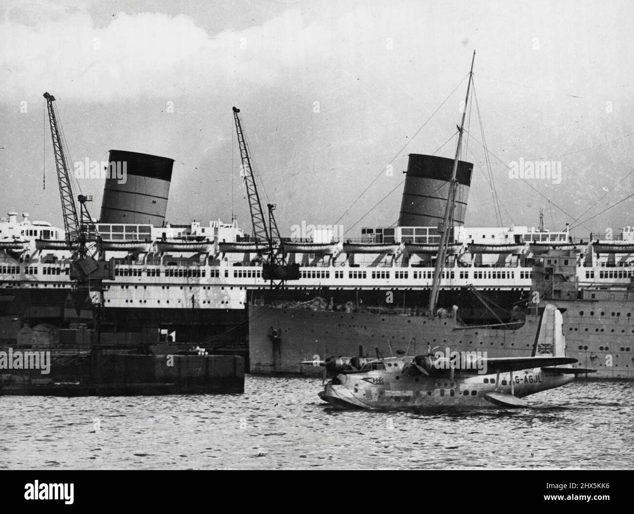 Ocean Links -- le gros de 85 000 tonnes de la reine Elizabeth, juste à New York, éclipse le bateau à vol de British Overseas Airways Corporation, qui s'amarre d'Australie, au nouveau terminal maritime de Berth 50 ici. 05 avril 1948. Banque D'Images