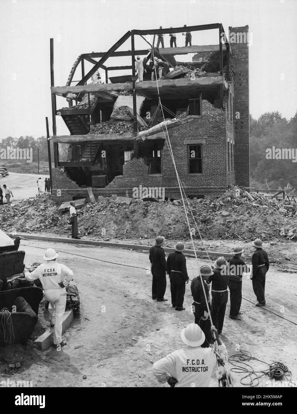 « Rescue Street » de l'Administration fédérale de la défense civile -- Une « victime » est abaissée dans un « claque à vie » de la « ruine » d'un immeuble de bureaux et d'appartements de trois étages, faisant partie de l'école de surveillance et d'entraînement de sauvetage de la FCDA, Olney, Md., le 21 janvier 1955. Banque D'Images