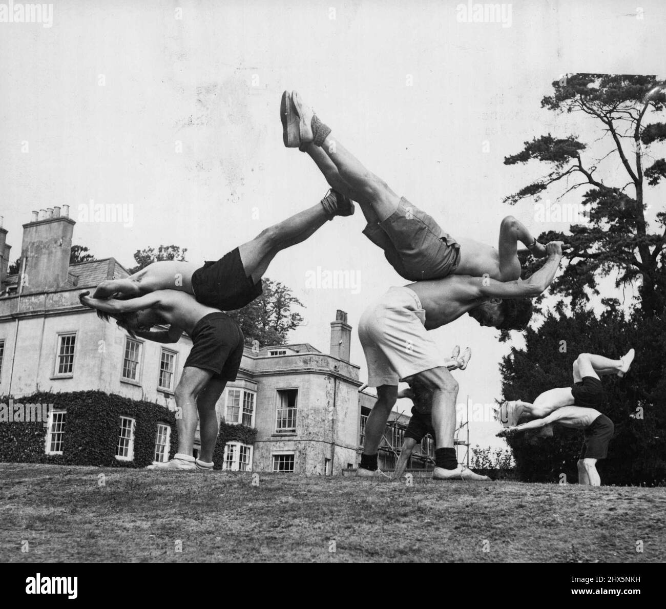 Les Allemands apprennent la voie britannique -- exercices de gymnastique avec un bâton. Les garçons apprennent à improviser à la T.P., aux sports et à d'autres branches du leadership des jeunes. En ajoutant des demi-pennies à leurs frais de cantine et des centimes sur les frais de table de billard dans leurs clubs, les garçons de Londres ont recueilli £80 pour rencontrer les tarifs et les dépenses de huit jeunes allemands prenant maintenant un cours dans le leadership de club de jeunesse à Amersha, Bucks. Les Allemands sont tous connus sous leur nom chrétien, tout comme les garçons français, hollandais et britanniques qui participent également au cours. Leur temps est passé dans l'artisanat, la poterie, la fabrication de marionnettes, le sport, P.T., Banque D'Images