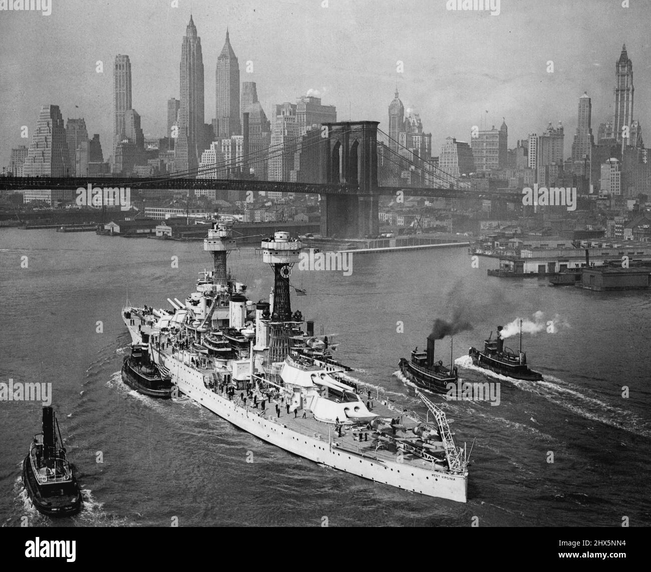 New York... Un cliché impressionnant de l'URSS Virginie occidentale, l'un des plus puissants chariots de combat de l'oncle Sam. Comme elle a fait la vapeur majestueusement le long de la rivière est sous le pont de Brooklyn aujourd'hui au début de son long voyage de retour au Pacifique. L'imposant horizon de Manhattan en arrière-plan forme un cadre frappant pour le navire comme elle dit Au revoir à la maison du père Knickerbocker où elle avait été programmée pour jouer un rôle important dans les célébrations de la foire mondiale jusqu'à ce qu'on lui ordonne de revenir sur la côte ouest avec d'autres navires de la parc. 06 juin 1939. (Photo par International News photo). Banque D'Images