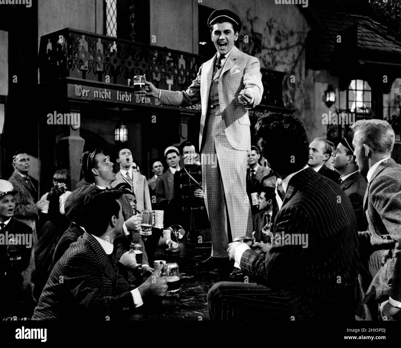 La chanson de boire....Edmund Purdom et les étudiants de Heidelberg dans une présentation musicale du "Prince étudiant" de M-G-M. « The Student Prince », filmé en Cinéma Scope et en couleur, les stars Ann Blyth, Purdom, John Ericson, Louis Calhern et la voix chantante de Mario Lanza. Richard Thorpe réalisé et Joe Pasternak produit à partir du script de William Ludwig et Sonya Levis. 26 juillet 1954. Banque D'Images