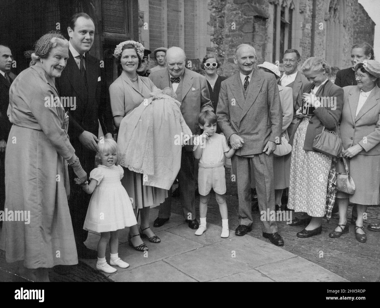 Un petit-enfant de Churchill est baptisé -- le premier ministre britannique Winston Churchill est heureux avec sa famille après le baptême de son huitième petit-enfant, Jeremy Soames, à Westerham, église de Kent à jour (dimanche). La mère, Mme Christopher Soames (anciennement Mary Churchill, fille du premier ministre), tient le bébé. Un parrain, le vicomte de Field Marshal Montgomery claque la main du frère du bébé, Nicholas. À gauche, Mme Clementine Churchill, épouse du premier ministre, tient la sœur du bébé, Emma, avec le capitaine Christopher Soames. 17 août 1952. (Photo de Reuterphoto). Banque D'Images