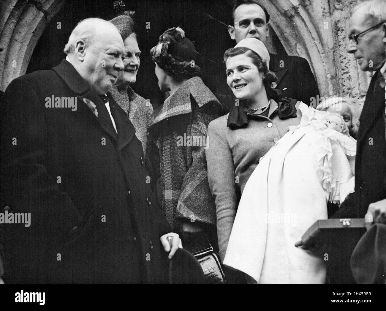 Churchill assiste au baptême -- de gauche à droite: Winston S. Churchill; Mme Clementine Churchill; femme non identifiée; Mme Mary Soames avec le bébé; homme non identifié sur le porche de l'église après la cérémonie. À l'arrière se trouve le père, le capitaine Christopher Soames. Le chef conservateur britannique Winston S. Churchill et son épouse Clementine ont assisté à la baptême de leur petit-enfant, fille de deux mois du capitaine Christopher Soames et de l'ancienne Miss Mary Churchill, à l'église paroissiale du 13th siècle de Flating, Sussex, en Angleterre, cet après-midi du 6 novembre. Le bébé a été baptisé Emma Mary. Banque D'Images