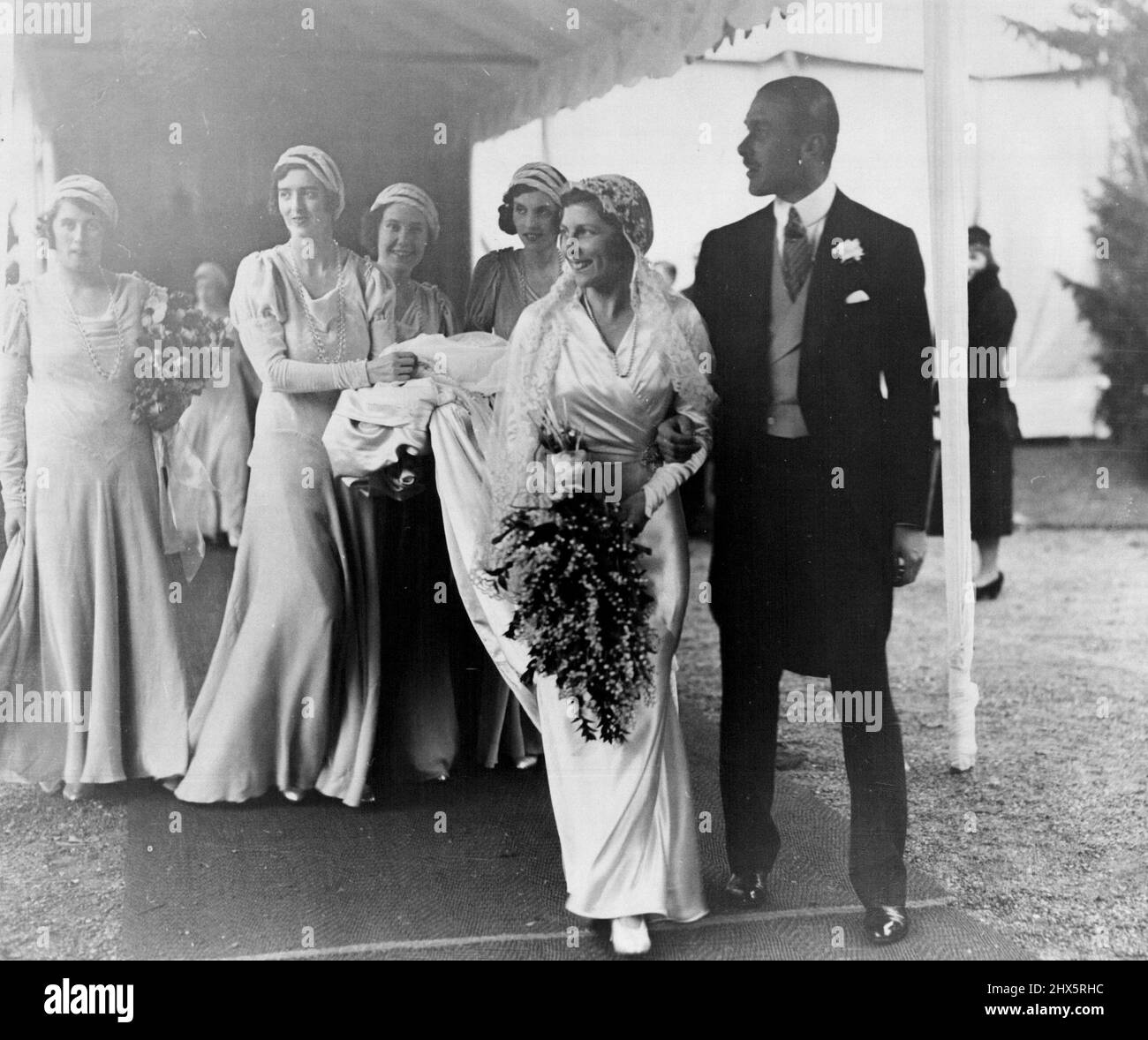 Lady May Cambridge a le sourire heureux alors qu'elle quittait l'église Balcombe, dans le Sussex, avec son époux, le capitaine Abel Smith. Elle était rayonnante dans sa robe de satin chatoyant, et le voile de dentelle Honiton prêté par la Reine, qui l'a porté à son propre mariage. 16 décembre 1931. Banque D'Images