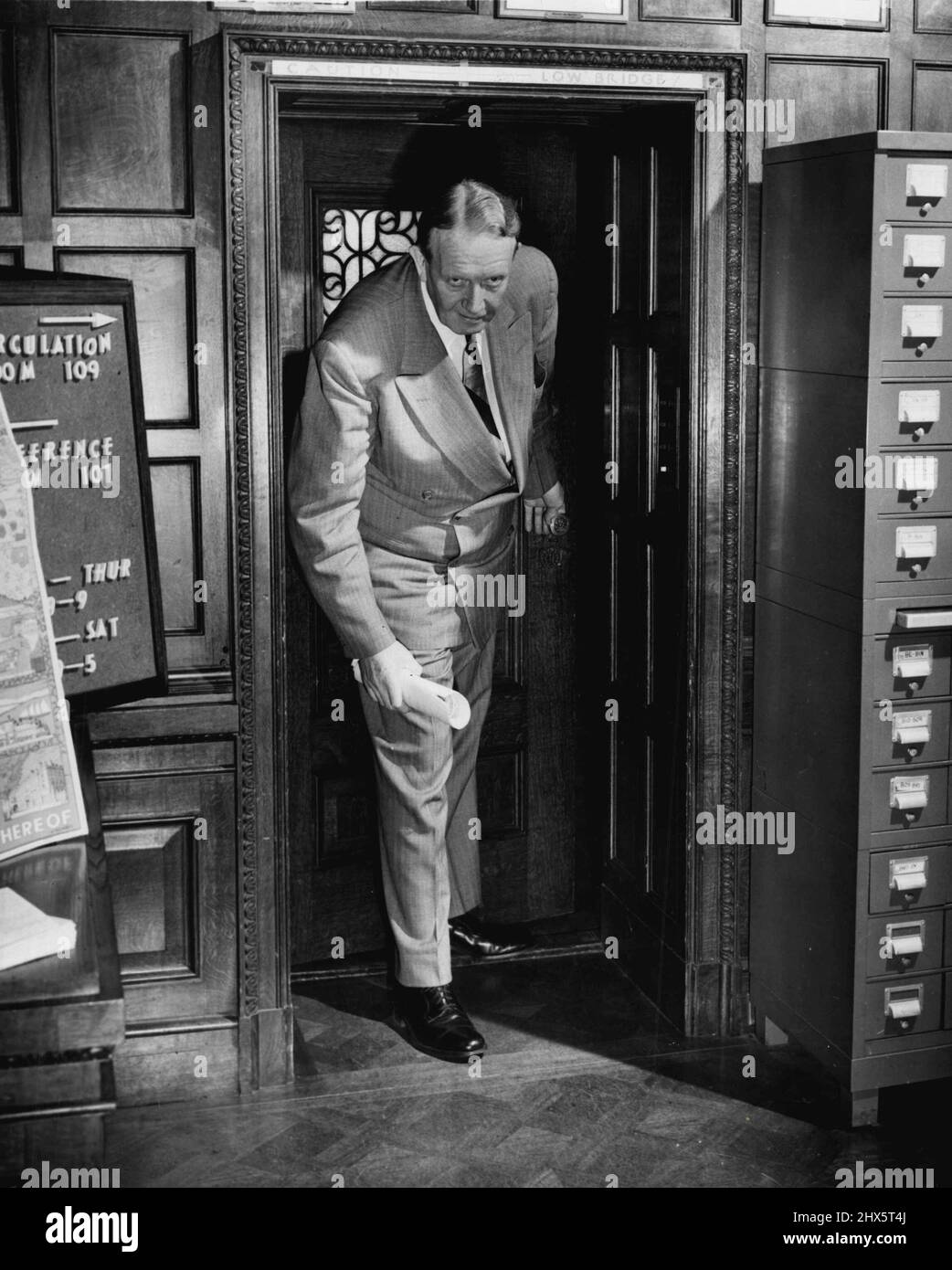 Etude dans la splendeur (cinquième de six) -- Dean Kenneth D. Johnson, un six pied de page, a à canard de passer par la porte de la bibliothèque, une ouverture basse construite pour accueillir le cadre de cinq pieds, deux pouces de Carnegie. Richement ornée de bois sculpté, la bibliothèque possède de nombreuses citations préférées de Carnegie sculptées sur les murs. 3 mai 1954. (Photo de United Press). Banque D'Images