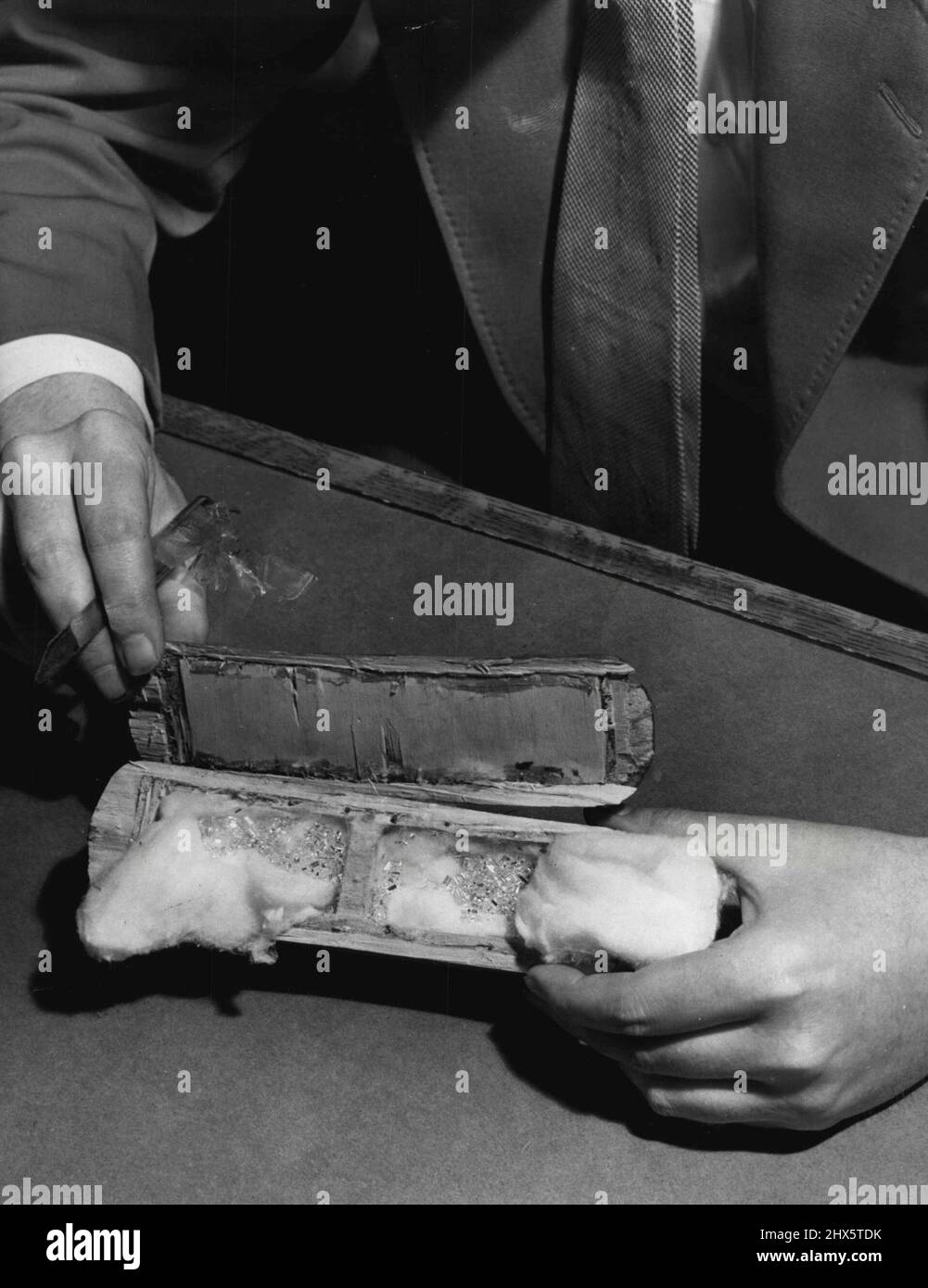 Plus de 100 petits diamants non coupés d'un montant d'environ 100 carats et d'une valeur de $50 000 ont été trouvés i la brosse de vêtements creux montré ici, par un agent des douanes des États-Unis à New York. 14 décembre 1955. (Photo par photo de presse associée). Banque D'Images