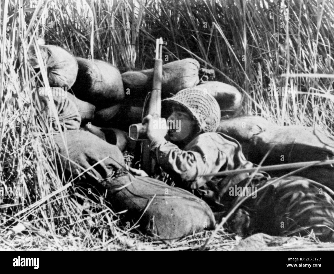 Une boisson d'eau pour Un US Jungle Fighter -- entouré d'une grande herbe de kunai, un sergent de l'armée américaine boit de l'eau de sa cantine pendant qu'il attend l'ordre d'attaquer les JAP de son trou de renfall sur le front de Buna en Nouvelle-Guinée où les forces alliées ont organisé une offensive réussie. 22 mars 1943. (Photo d'Interphoto News Pictures Inc.). Banque D'Images