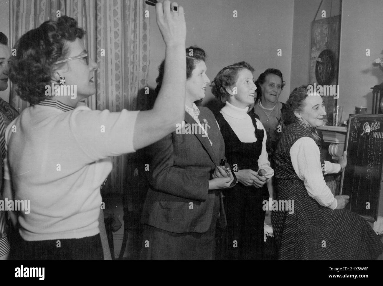 Le Windsor Castle Hotel de Paddington, à Sydney, possède un club de fléchettes pour femmes, dont les membres jouent à l'une de leurs sessions du mardi. La secrétaire est Mme Betty Palmer (en chandail blanc). 21 septembre 1955. Sports, sport, athlète, athlétique, Banque D'Images