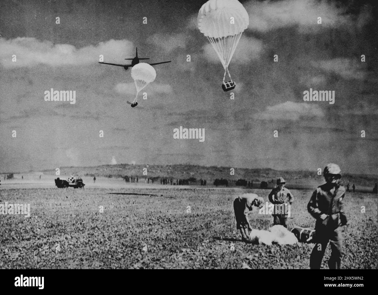 Les Marines des États-Unis sur Iwo Jima reçoivent le courrier de Parachute -- les Marines des États-Unis rassemblent des paquets de courrier parachuté qui leur sont déposés par un avion de transport pendant leur combat amer sur Iwo Jima, avant-poste militaire japonais à 750 miles (1200 kms.) de Tokyo, capitale du Japon. Les Marines, avec un fort soutien de l'artillerie, ont conduit les Japonais à la pointe nord de l'île volcanique en trois semaines de combats furieux. En mars 12, ils avaient coupé les restes de la garnison japonaise en deux petites poches, chacune occupant Banque D'Images