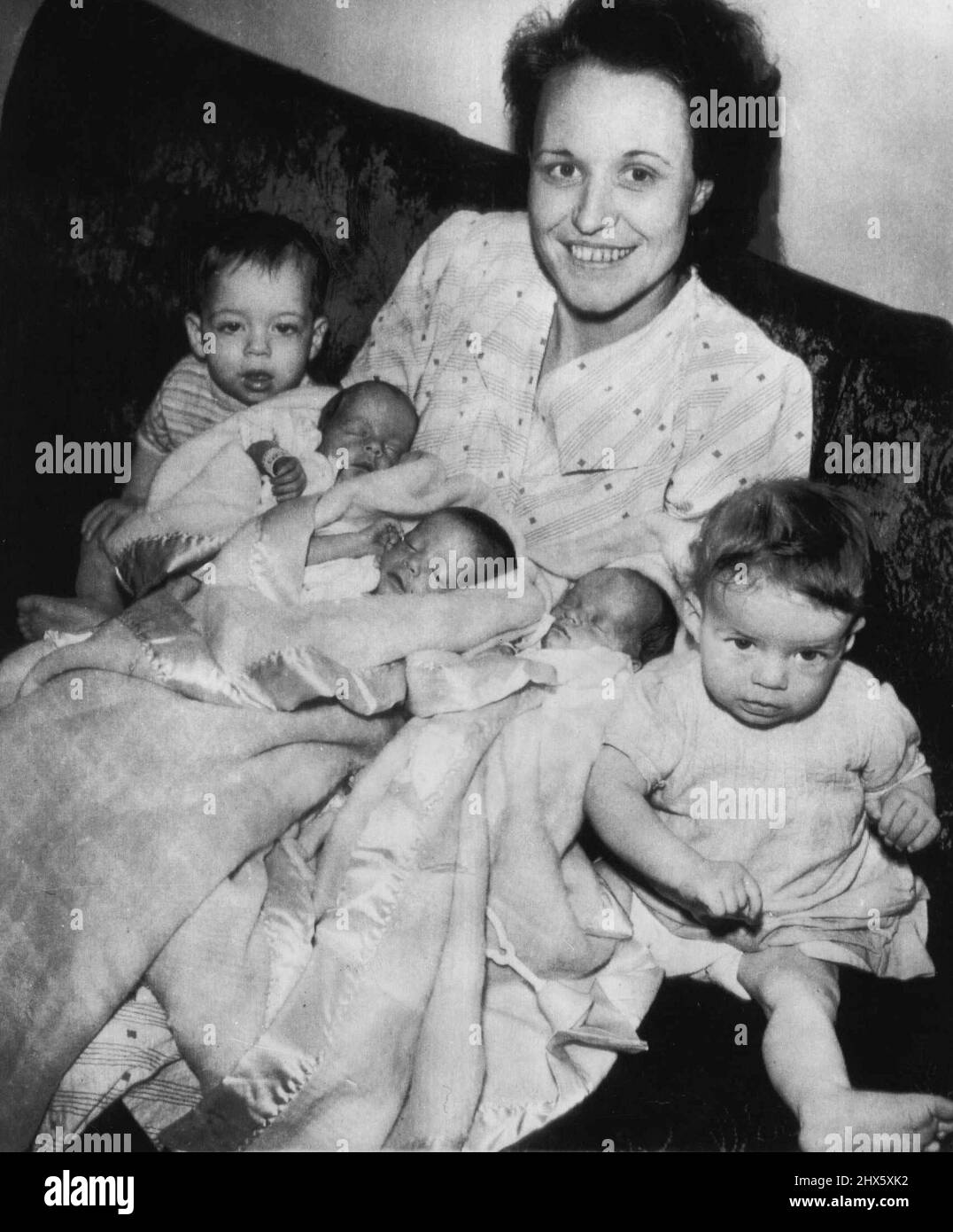 Jumeaux, triplés nés de mère dans un an -- « Noël sera différent cette année », explique Mme Thelma Gibbs (au centre) comme elle est assise ici entouré de bébés -- aucun d'entre eux n'était ici à la même époque l'année dernière. Son conseil aux mères est pour beaucoup de patience et une bonne machine à laver, mais les Gibbses n'ont pas de machine. La mère de vingt-sept ans a identifié les jumeaux de 11 mois comme Wayne et Jane (à gauche et à droite), et les triplés comme Lynda, Brenda et Glenda (de gauche à droite), un mois Banque D'Images