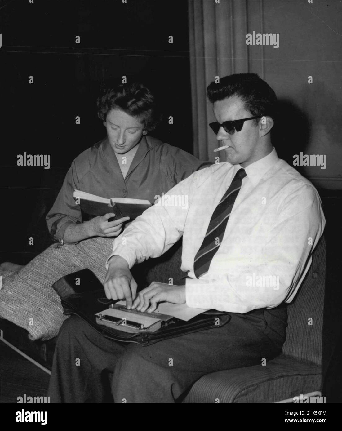 Blind Student obtient un baccalauréat -- elle est âgée de 21 ans Afred Adanez en utilisant sa machine à écrire en braille en répondant aux questions lues par Pamela Dixon, étudiante de 20 ans. Il a obtenu son baccalauréat ès arts, mais il donne le mérite de son succès à ses neuf amis. Nuit après nuit, mois après mois sept filles et deux hommes étudiants se sont assis pour lire des boks d'étude à Alfred Adanez, 21 ans. Pour Alfred, aveugle depuis sa naissance, étudiait à l'Université de Liverpool pour son baccalauréat ès arts. Et beaucoup de la t Banque D'Images