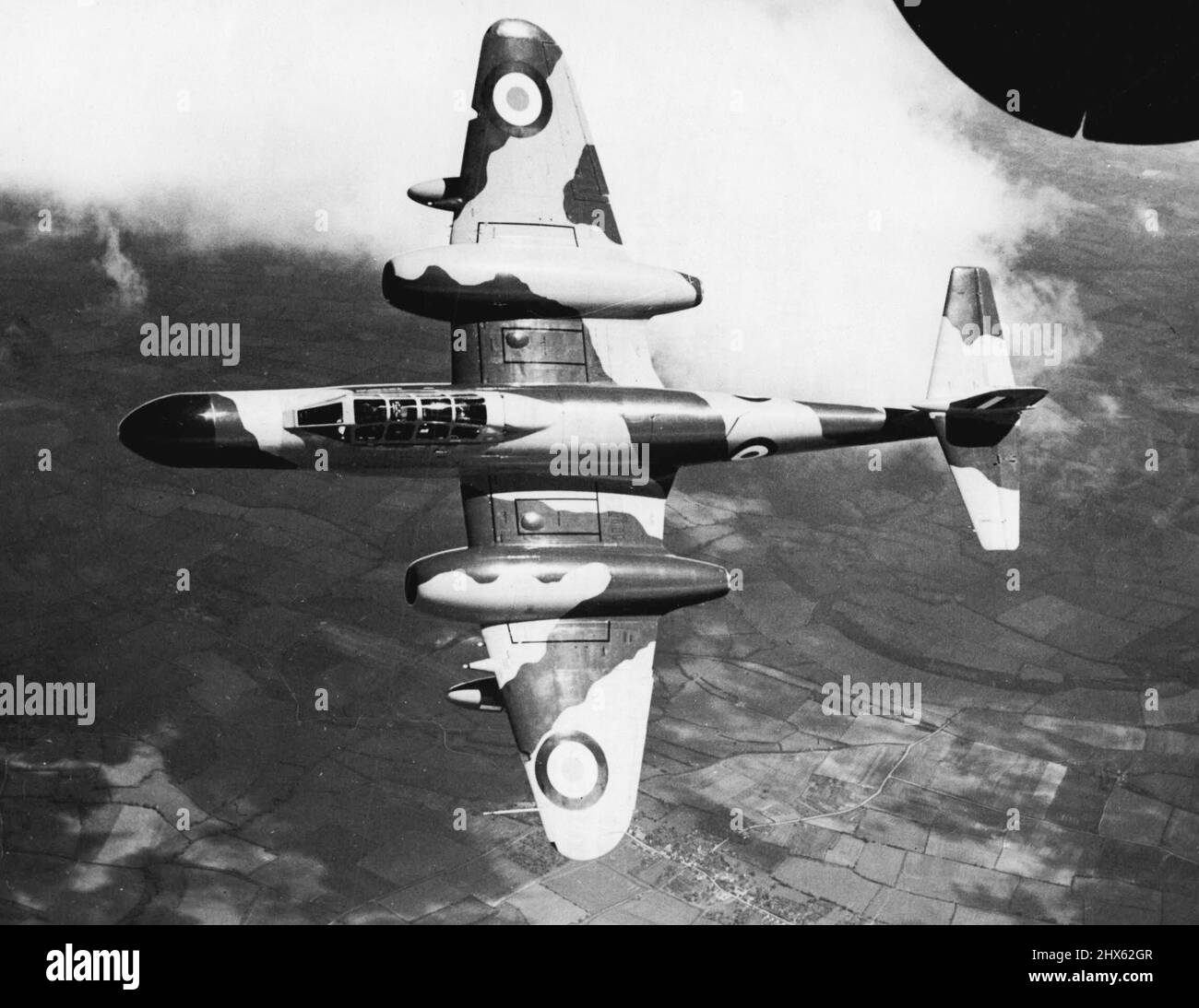 Plan at Elevation vu d'en haut comme il vole haut au milieu des nuages est un Armstrong Whitworth N. F. 11 de nuit. Combattant de nuit standard de la Royal Air Force, le N.F.11 est alimenté par deux turbines à gaz Rolls-Royce 'derwon' et possède quatre canons de 20mm. Montés par paires dans les ailes extérieures des sacelles du moteur. Son équipement radar est porté dans le nez étendu. L'avion a une envergure de 43 pieds, une longueur de 48ft. Gin. Et une hauteur hors tout de 13ft. 11in. 18 juillet 1954. (Photo de Reu Banque D'Images