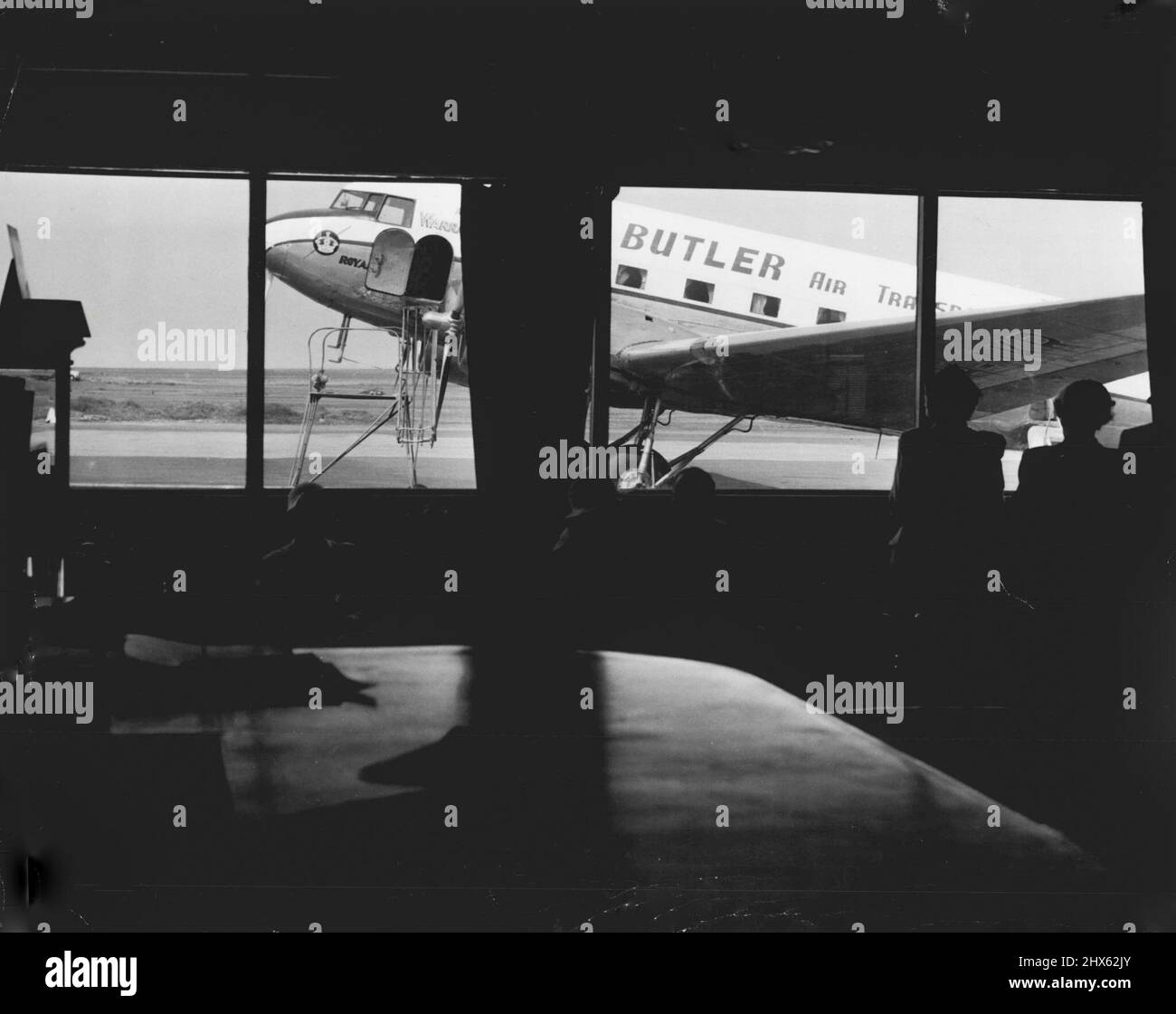 Les passagers voient un DC3 de ***** FLOTTE DE CHAUVES-SOURIS par les fenêtres du terminal de Mascot. 30 novembre 1955. Banque D'Images