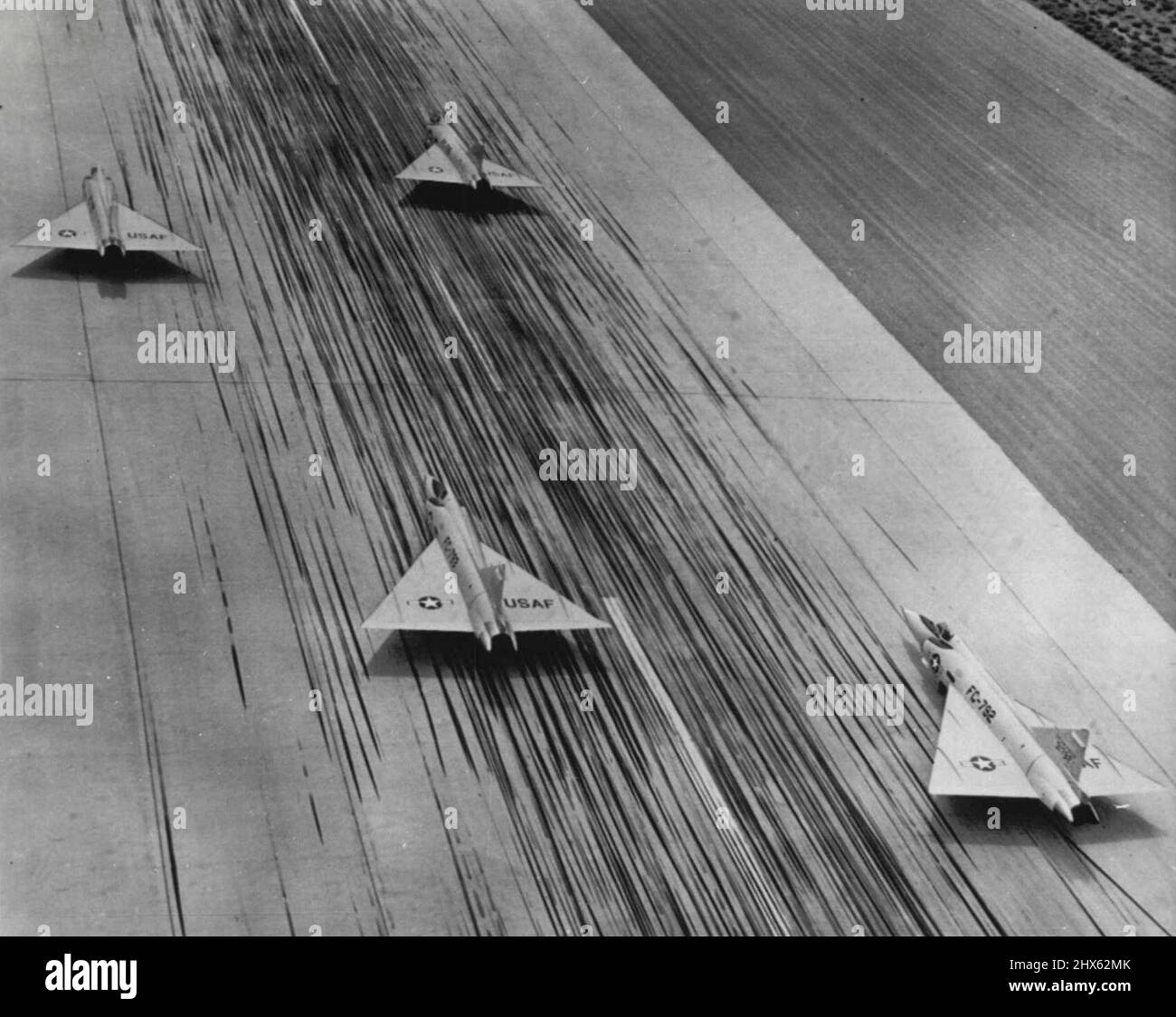 Illusion de vitesse - ces quatre intercepteurs de jet Convair F-102A tout temps semblent courir sur la piste de Palmdale, Calif. Les avions sont encore debout mais l'illusion de vitesse vient des intercepteurs d'aile delta en rationalisant et des centaines de stries de pneu laissées sur la piste de béton par avion d'atterrissage. 04 octobre 1955. (Photo par AP Wirephoto). Banque D'Images