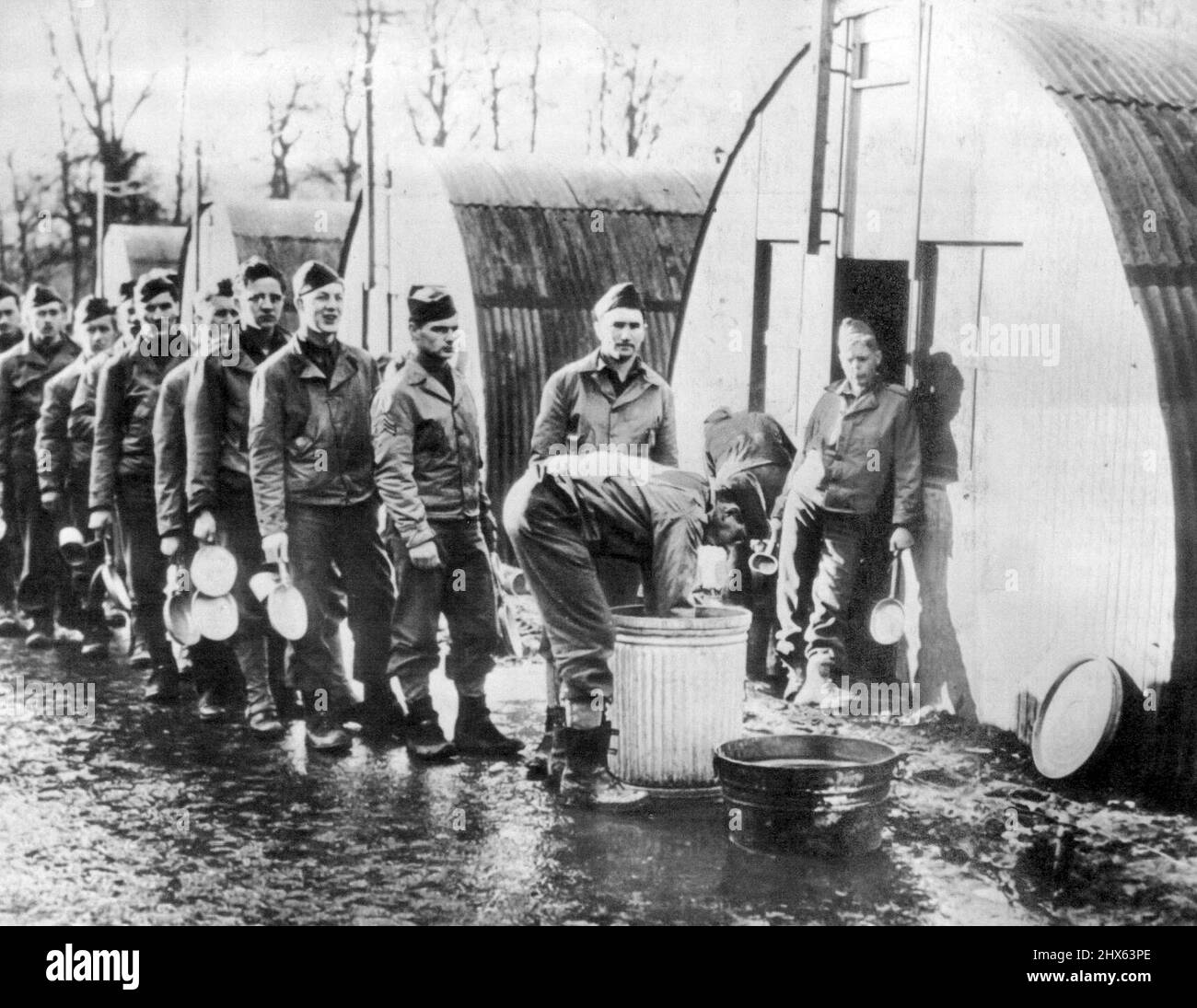 Temps de lavage de la vaisselle pour A.E.F. - Les soldats des États-Unis 'quelque part en Irlande du Nord' se sont mis en file d'attente pour leurs kits de mess après un repas du soir de ragoût irlandais, de pain et de café. 24 février 1942. (Photo par AP Wirephoto). Banque D'Images