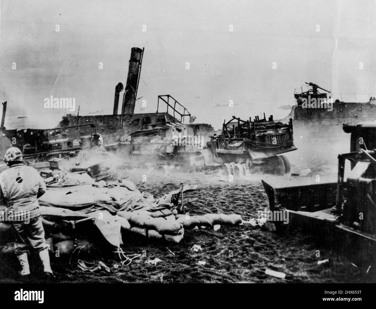 L'épave de la guerre, murmurée par le feu de croix des assaillants et des défenseurs d'Iwo Jima a parsemé la plage étroite où les Américains ont forcé leur atterrissage initial. Bulldozers les camions et jeeps, toujours flamboyants, sont encadrés par un transport de Jap vidé. 7 mars 1945. (Photo par US Office of War information photo). Banque D'Images