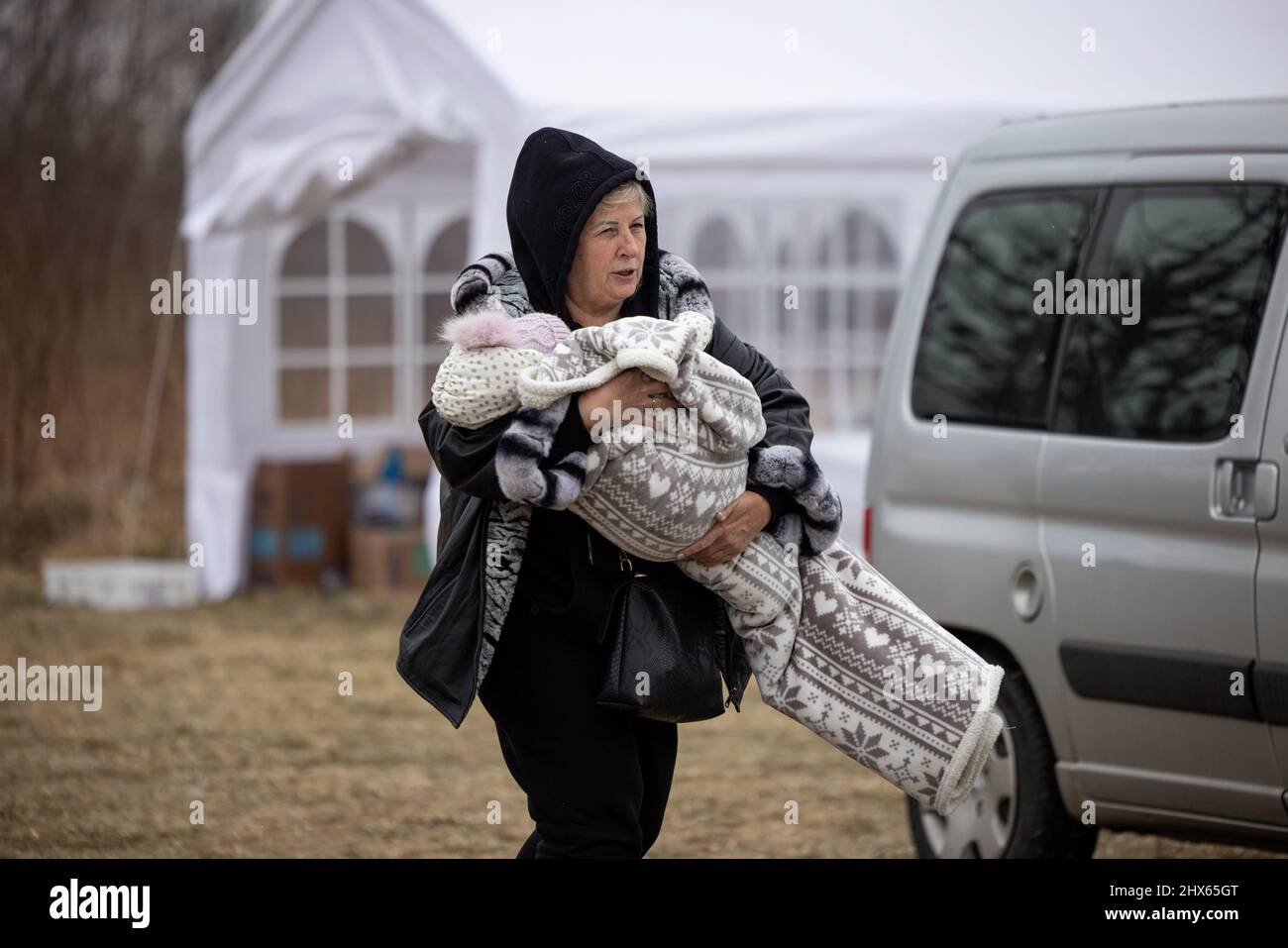 Przemysl, Pologne. 09th mars 2022. Une femme a vu porter son jeune enfant à l'extérieur du centre d'accueil des réfugiés.Un centre d'accueil temporaire des réfugiés a été installé dans un ancien entrepôt de Tesco, à la périphérie de Przemy?l, pour abriter des centaines de milliers de réfugiés ukrainiens qui fuient par la frontière entre Medyka et Shehyni. Crédit : SOPA Images Limited/Alamy Live News Banque D'Images