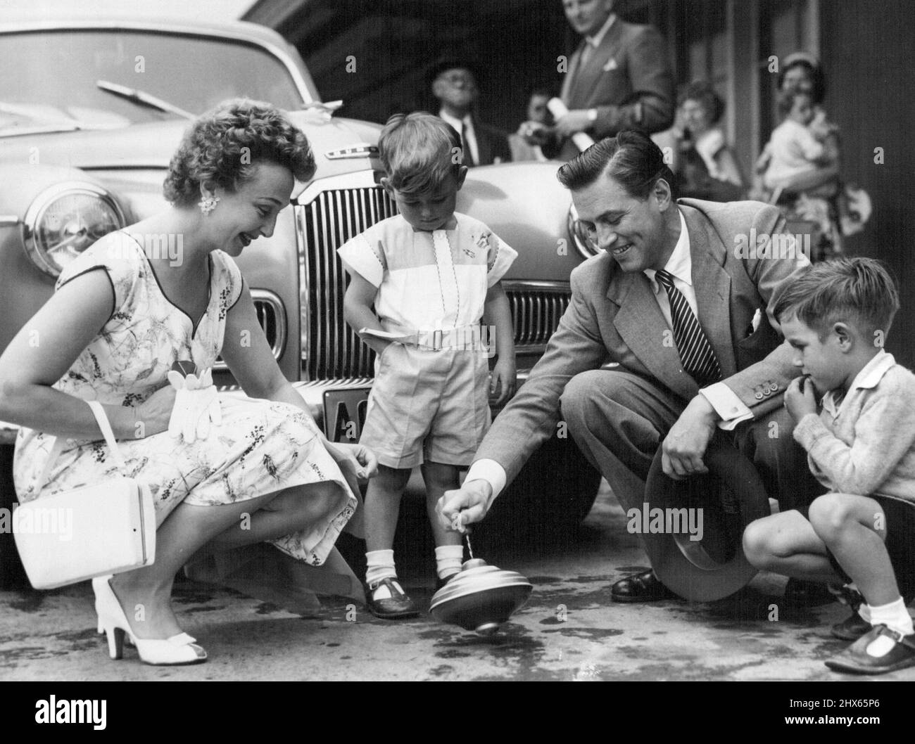 Lorsque les stars de cinéma Googie Withers et John McCallum ont acheté hier un haut de spinning pour leur fille de quatre ans Joanna, ils ont juste dû l'essayer à Castlereagh St. ils ont bientôt eu quelques spectateurs intéressés - Peter Spencer, 3 ans, de Newcastle (à gauche), et David Jackson, 5 ans, De Guildford. Les étoiles apparaîtront dans trois pièces pour J. C. Williamson. 11 janvier 1955. (Photo de l'agence de photographie australienne). Banque D'Images