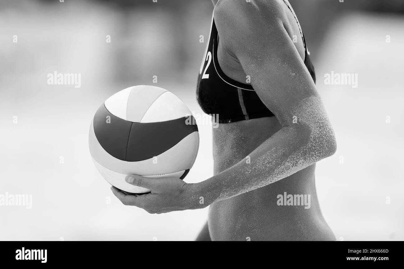 Un joueur de Beach volley féminin se met à l'épreuve pour servir le ballon en noir et blanc Banque D'Images