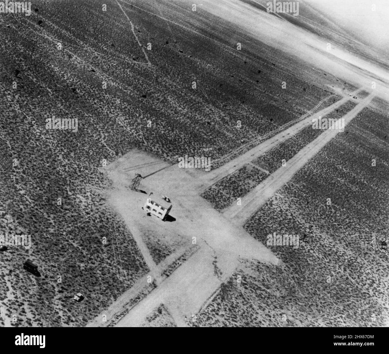 Blast site de l'air -- Voici une vue aérienne de la scène prise après l'explosion atomique d'hier. Au premier plan se trouve la Chambre no 2, qui est restée debout. En haut à droite à gauche des routes parallèles se trouve l'épave de la Chambre no 1. Au-delà, il y a un endroit noirci où se trouvait autrefois la tour en acier de 300 mètres au-dessus de laquelle l'explosion a eu lieu. Notez les autos dans le désert. 18 mars 1953. (Photo par AP Wirephoto). Banque D'Images