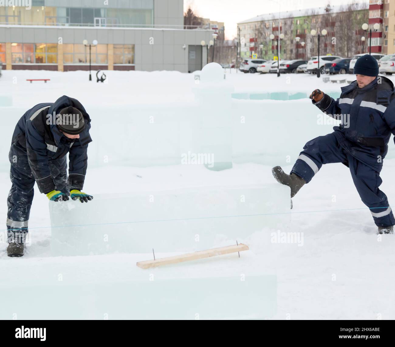 Les travailleurs en blouson bleu essaient de déplacer le panneau de glace avec leurs mains et leurs pieds. Banque D'Images