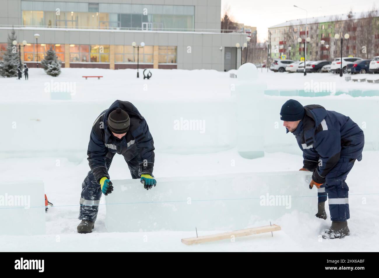 Les travailleurs en blouson bleu essaient de déplacer le panneau de glace avec leurs mains Banque D'Images