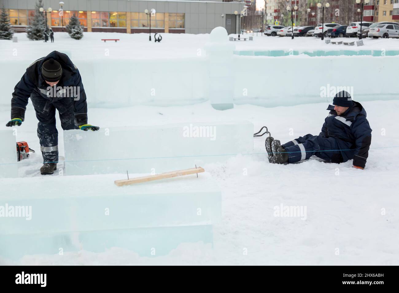 Les travailleurs en blouson bleu essaient de déplacer le panneau de glace avec leurs mains et leurs pieds. Banque D'Images