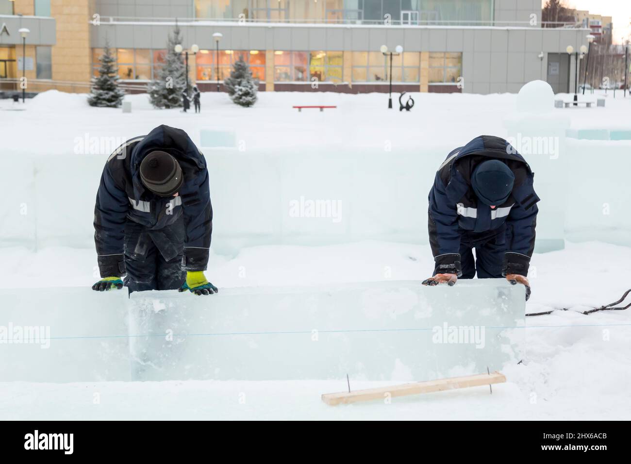 Les travailleurs en blouson bleu essaient de déplacer le panneau de glace avec leurs mains Banque D'Images