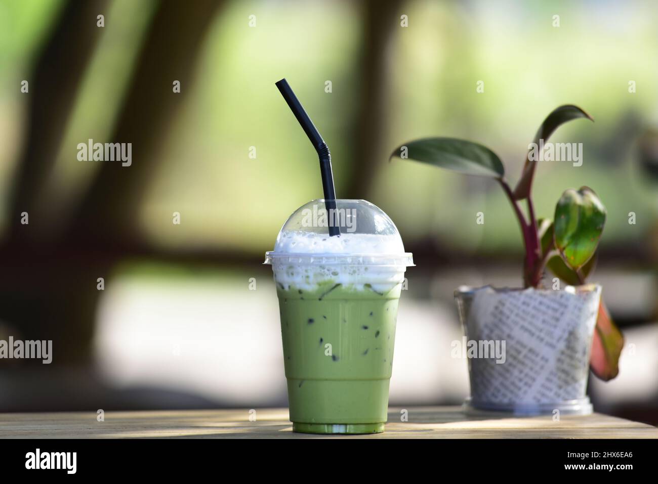 Gros plan d'une tasse en plastique de thé vert glacé ou de Matcha dans une tasse en plastique prête à boire, posez-la sur une table en bois. Banque D'Images
