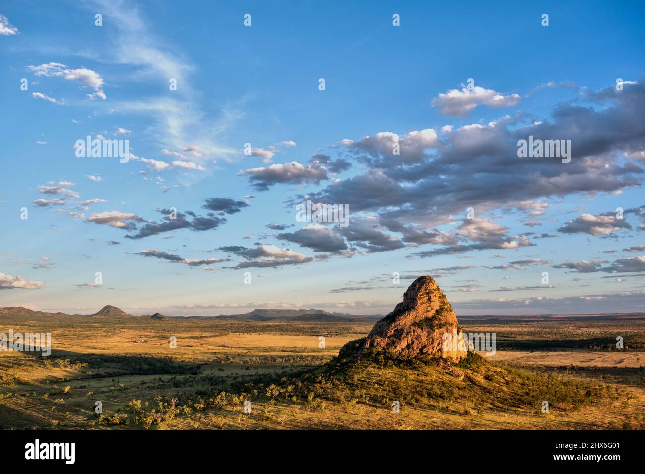 Lumière Golden Hour au-dessus d'un paysage accidenté avec une formation rocheuse proéminente sous un ciel couvert de nuages Wolfang Peak Qld Australie Banque D'Images