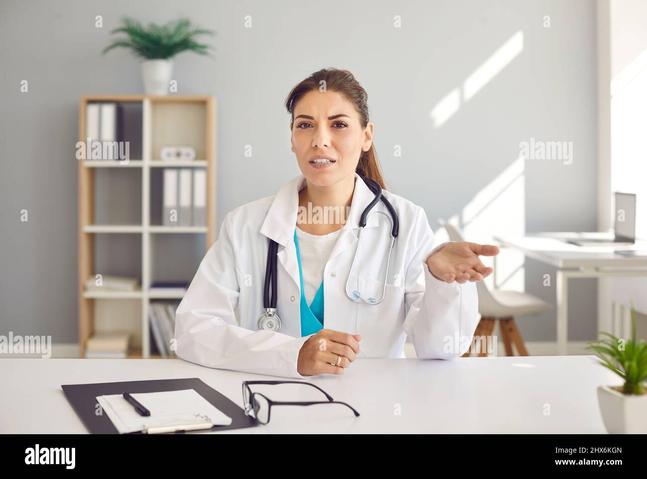Femme médecin assise à la table et donnant la consultation en ligne au patient sur appel vidéo Banque D'Images