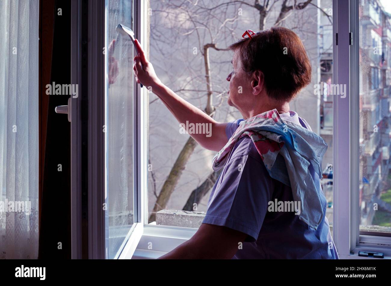 Portrait d'une femme âgée qui nettoie les fenêtres Banque D'Images