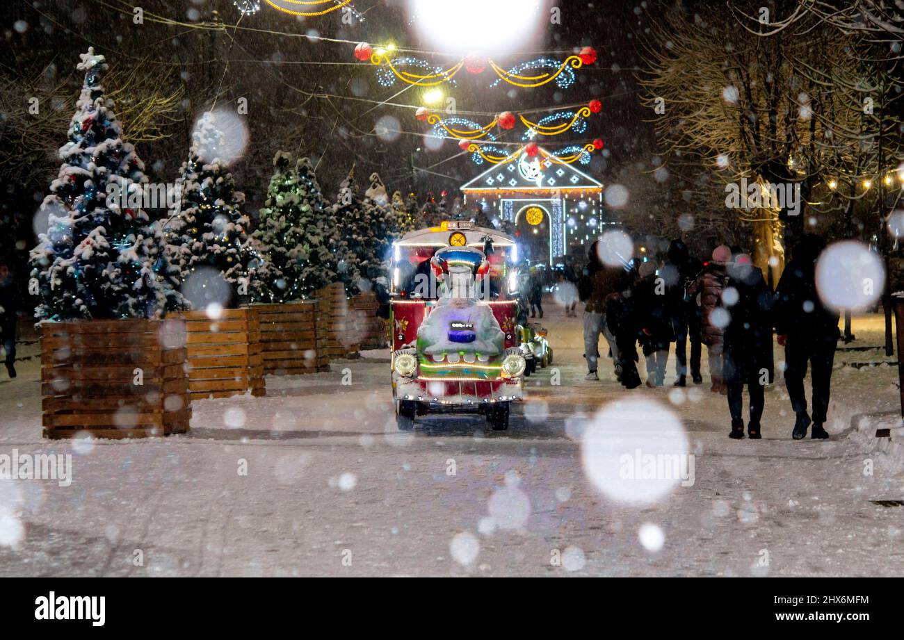 Rue enneigée de la ville avec arbres de Noël et décoration illuminée la nuit. Banque D'Images