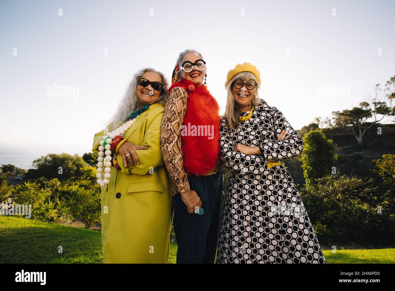 Des femmes matures et excentriques souriant à la caméra tout en se tenant ensemble dans un parc. Groupe de femmes âgées confiantes portant des vêtements décontractés colorés. TH Banque D'Images