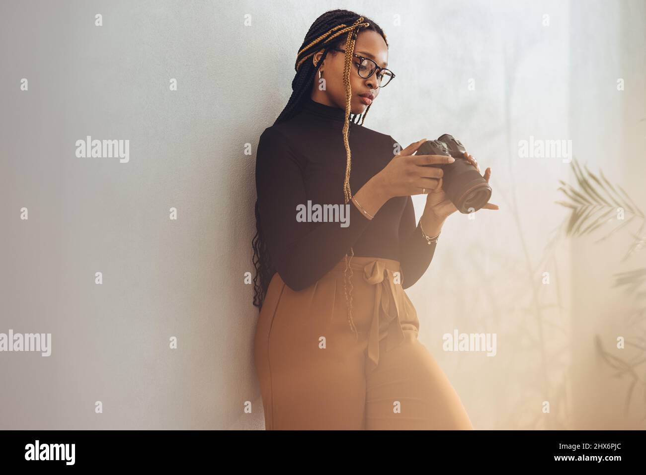 Préparation à un travail de caméra. Une photographe artistique qui a installé son appareil photo reflex numérique tout en étant debout dans son bureau. Femme créative indépendante Banque D'Images