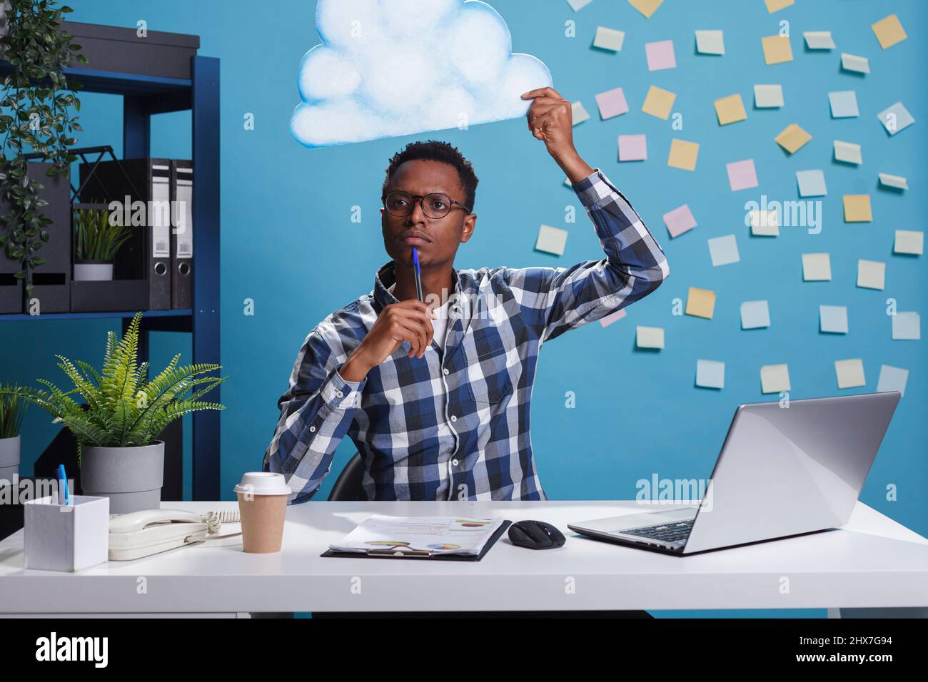 Entrepreneur réfléchi et concentré avec bulle de cloud au-dessus de la tête tout en pensant à la bonne planification d'entreprise. Homme intelligent à la recherche d'idées créatives tout en contemplant un espace de travail de bureau. Banque D'Images