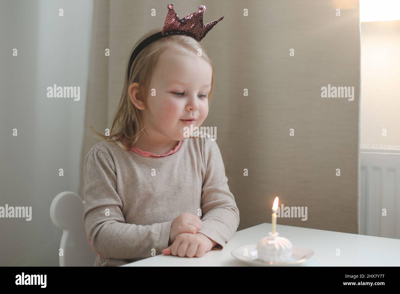une petite fille mignonne souffle une bougie sur un gâteau d'anniversaire à la maison. Anniversaire de l'enfant Banque D'Images
