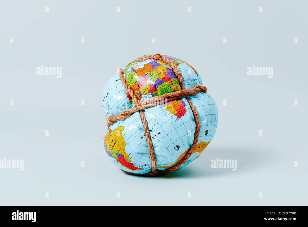 gros plan d'un globe terrestre étroitement attaché avec une corde sur un fond bleu pâle Banque D'Images