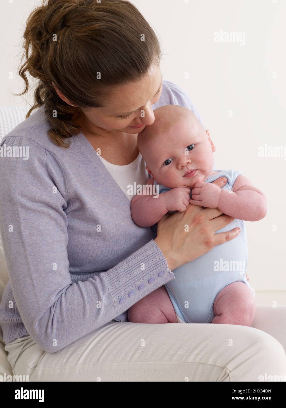 Jeune garçon tortueux, tenant le bébé droit et frottant en arrière, 6 semaines Banque D'Images